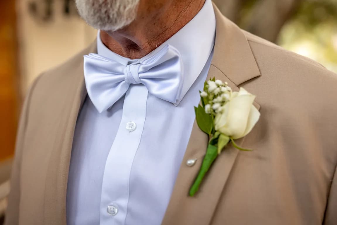 A white bow tie and a rose boutonniere