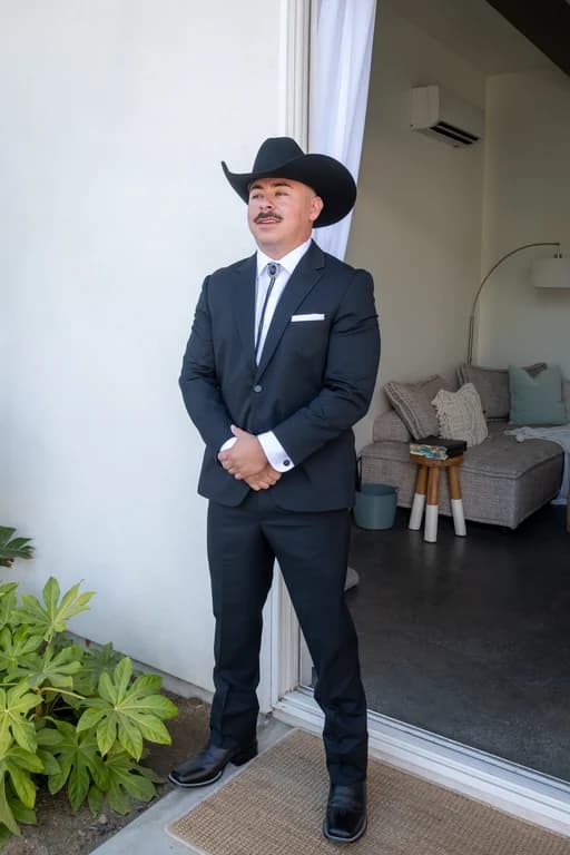 Josh in a black hat and suit, waiting