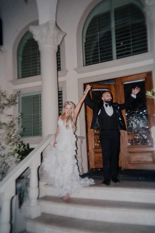 Jovin + Jordyn raising their arms at the front doors