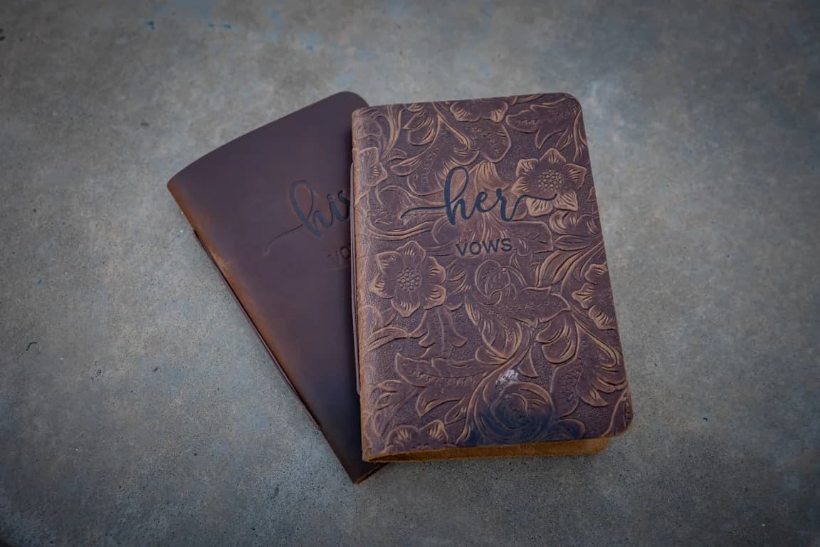 Two leather vow books, one stamped 'her vows'