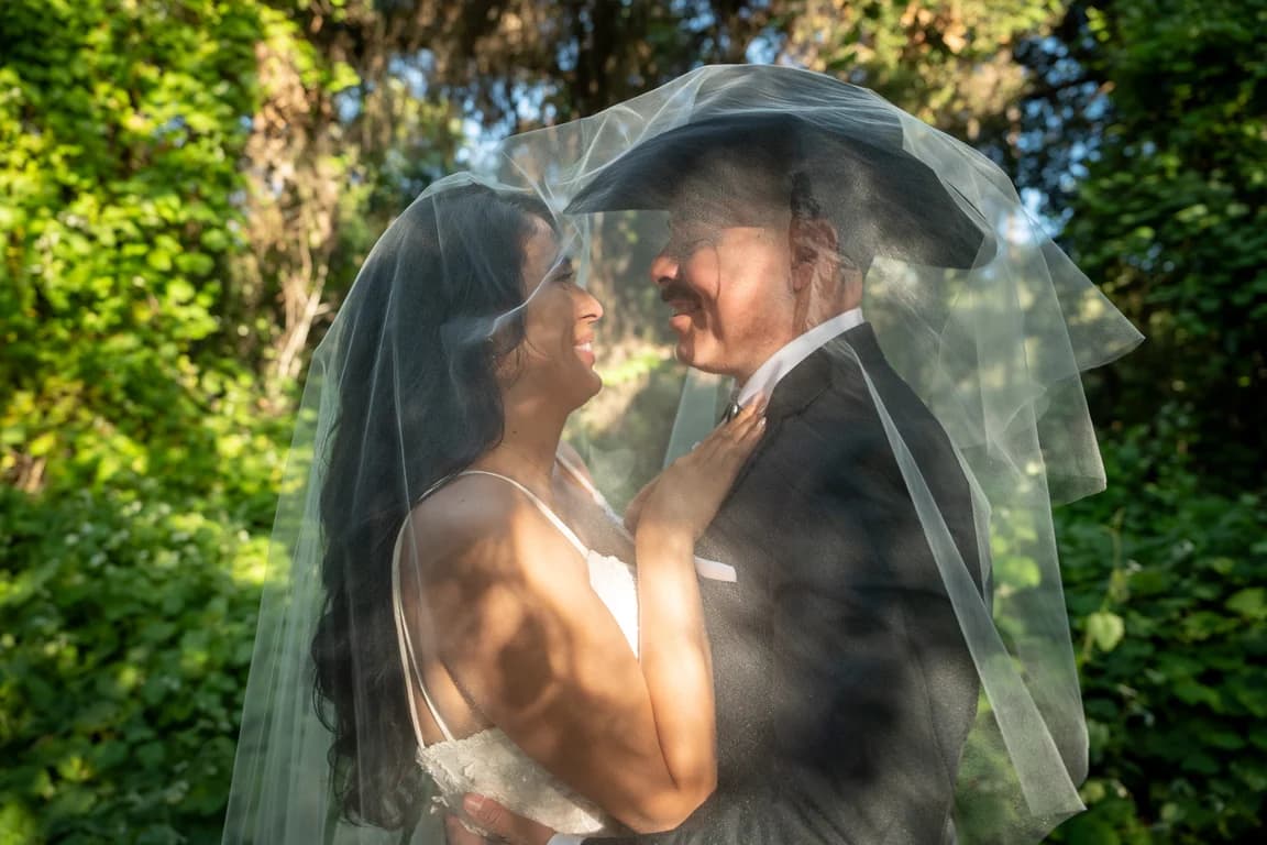 Josh + Julissa under her veil among the trees