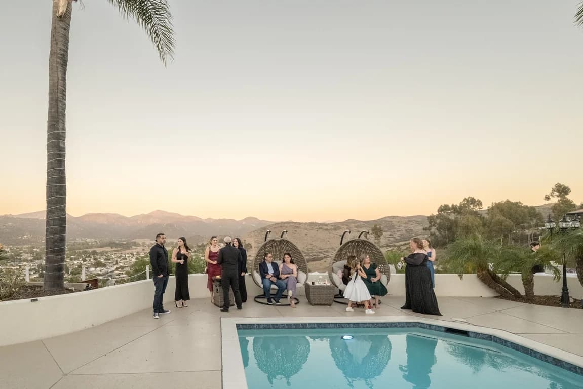 Guests on the pool terrace at dusk, the valley below