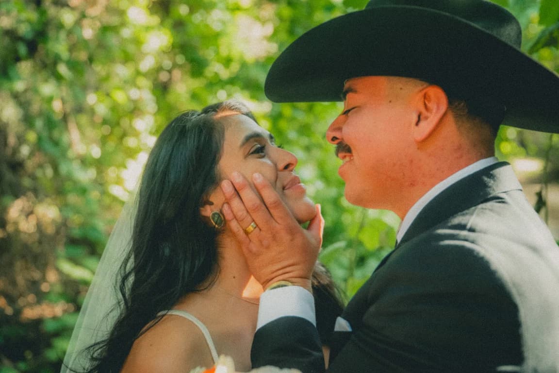 Josh in his black hat holding Julissa's face