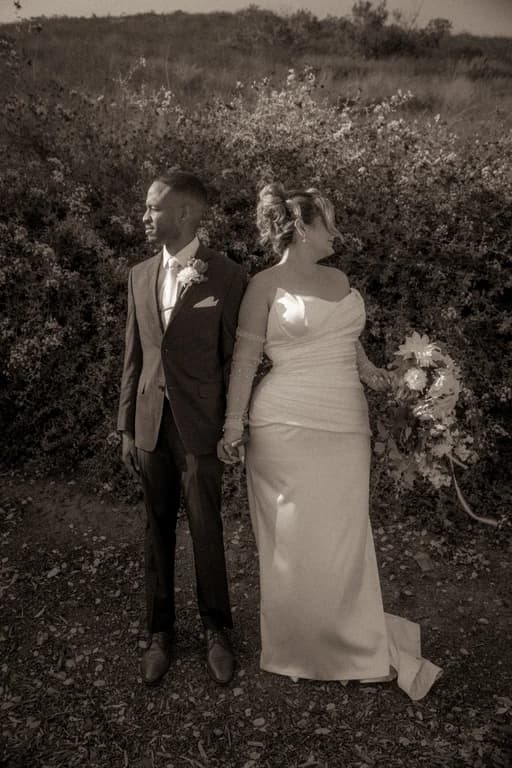 Brandon + Lola standing together by the hedge, in black and white