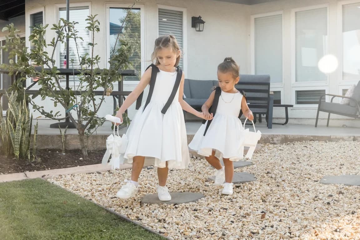 Two flower girls in white on the path to the ceremony