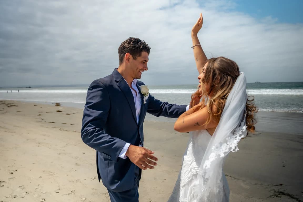Kiara laughing, arm raised, with Niko on the beach