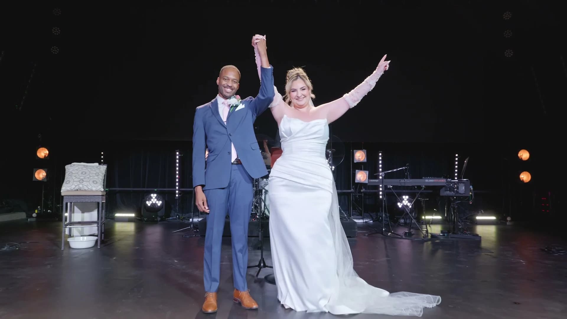 Brandon + Lola raising their hands on stage after the ceremony