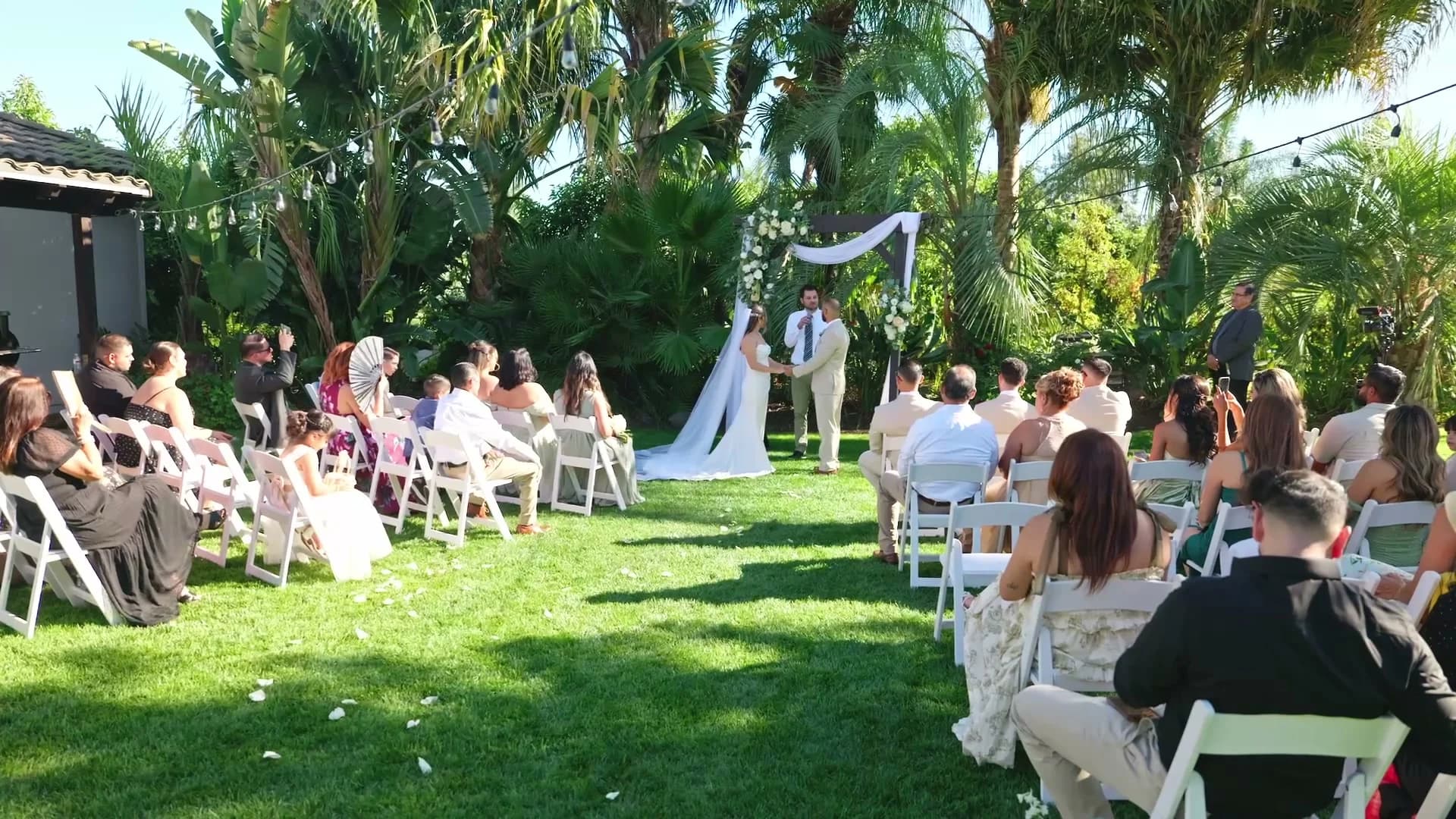 Guests watching the ceremony in the backyard, the arch at the end of the aisle