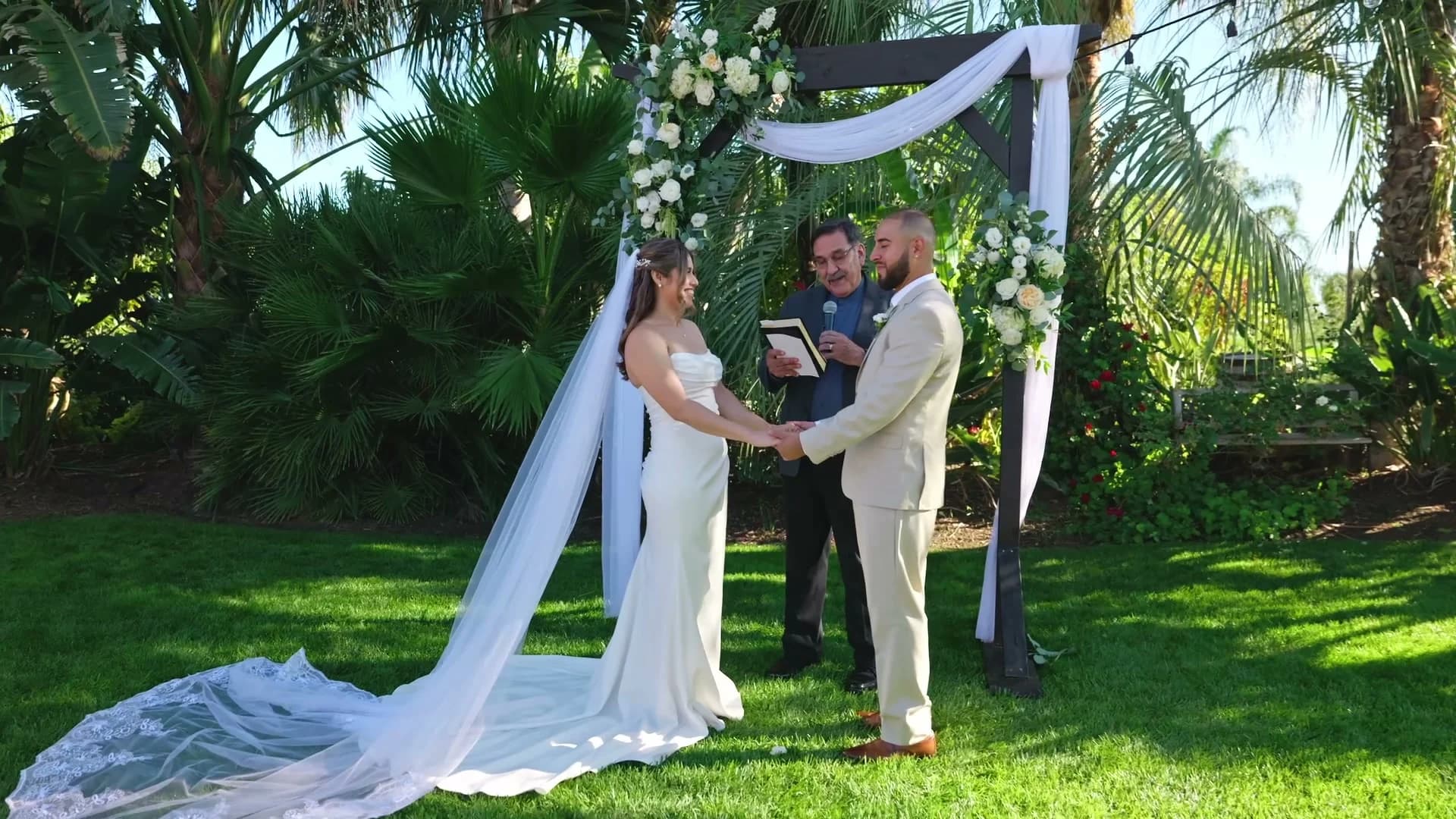 Ivan + Yesenia holding hands at the arch during the vows