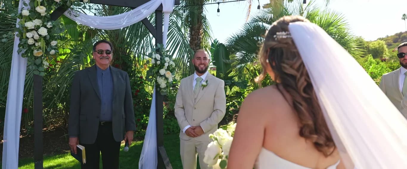 Ivan smiling at the arch as Yesenia comes down the aisle