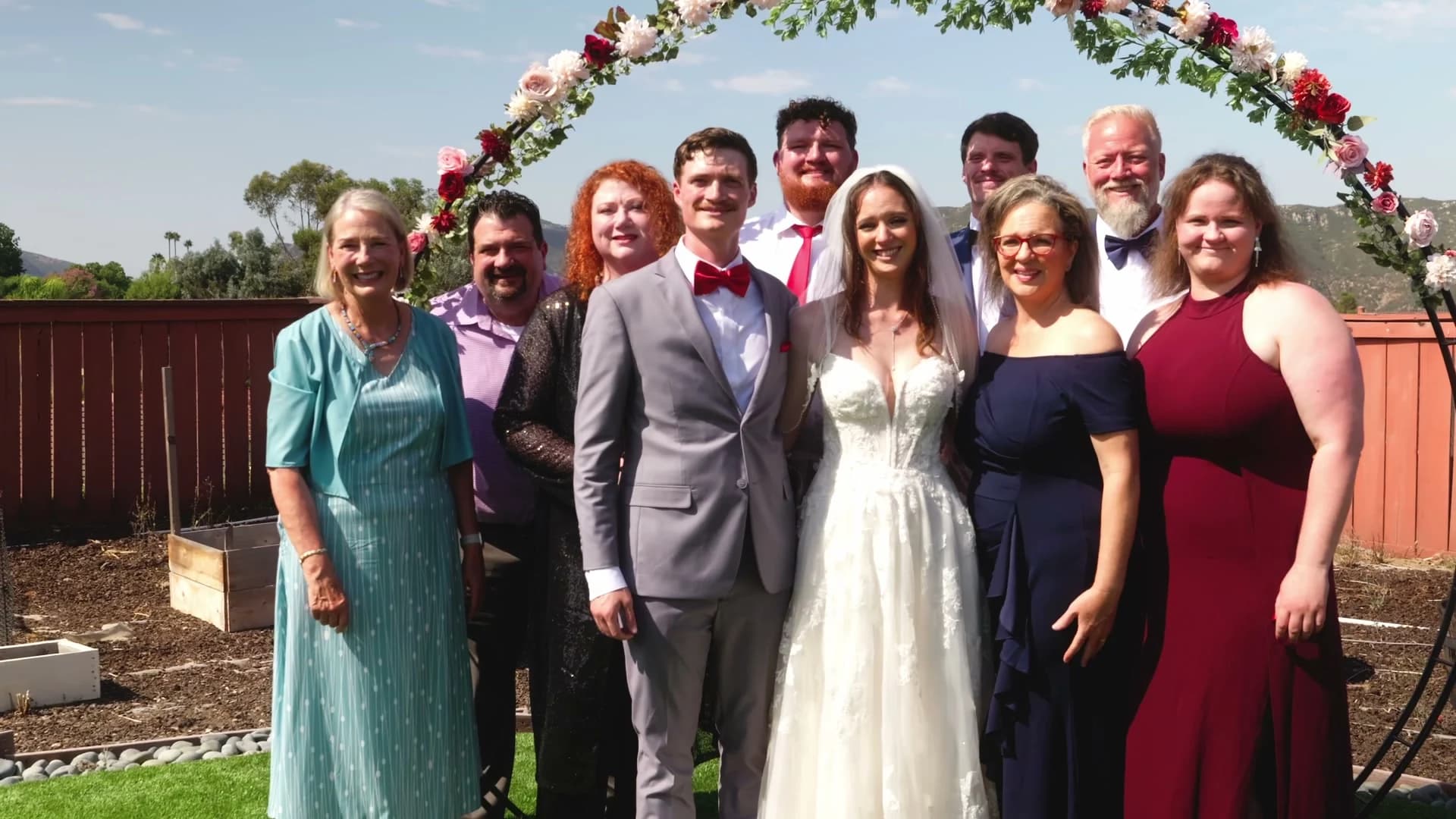 Jonathan + Lizzy with family under the floral arch