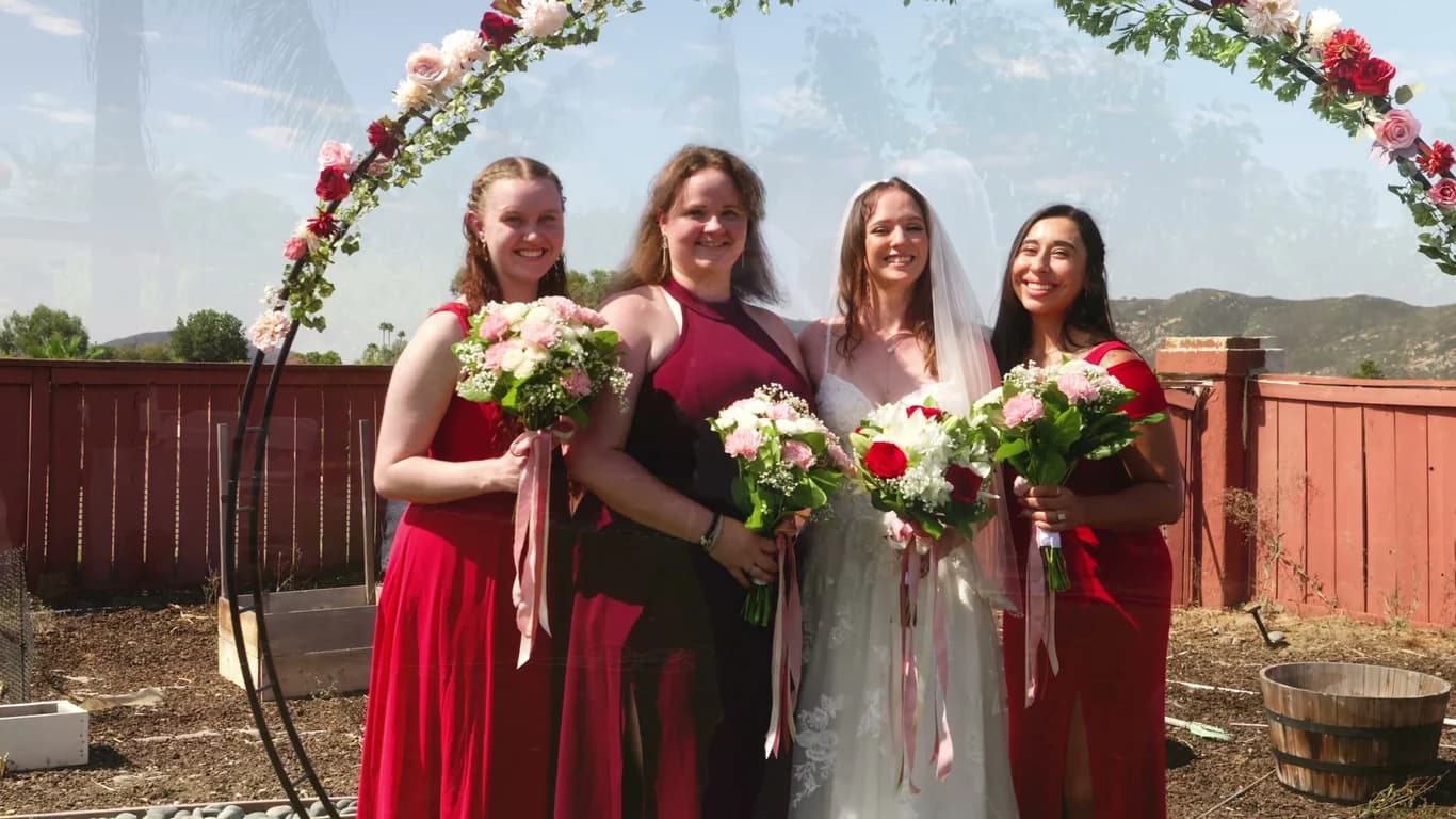 Lizzy with her bridesmaids in red, bouquets of pink and red roses