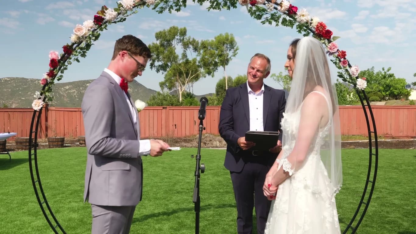 Jonathan reading his vows as the officiant smiles