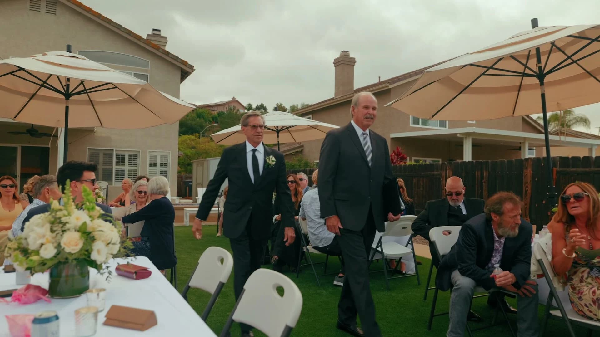 Guests at round tables under white umbrellas around the pool