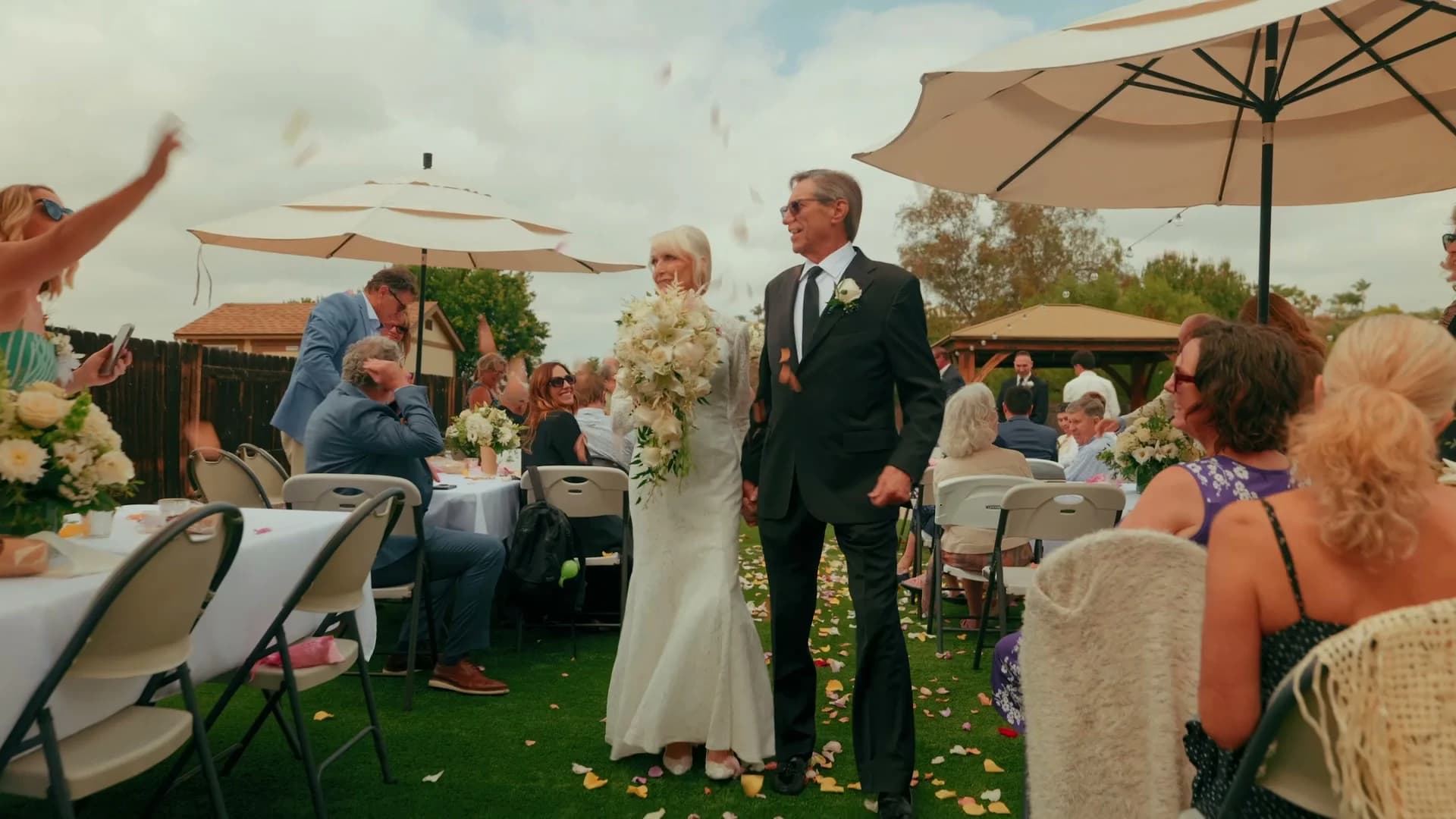Luana + Charles walking back up the aisle as guests throw petals