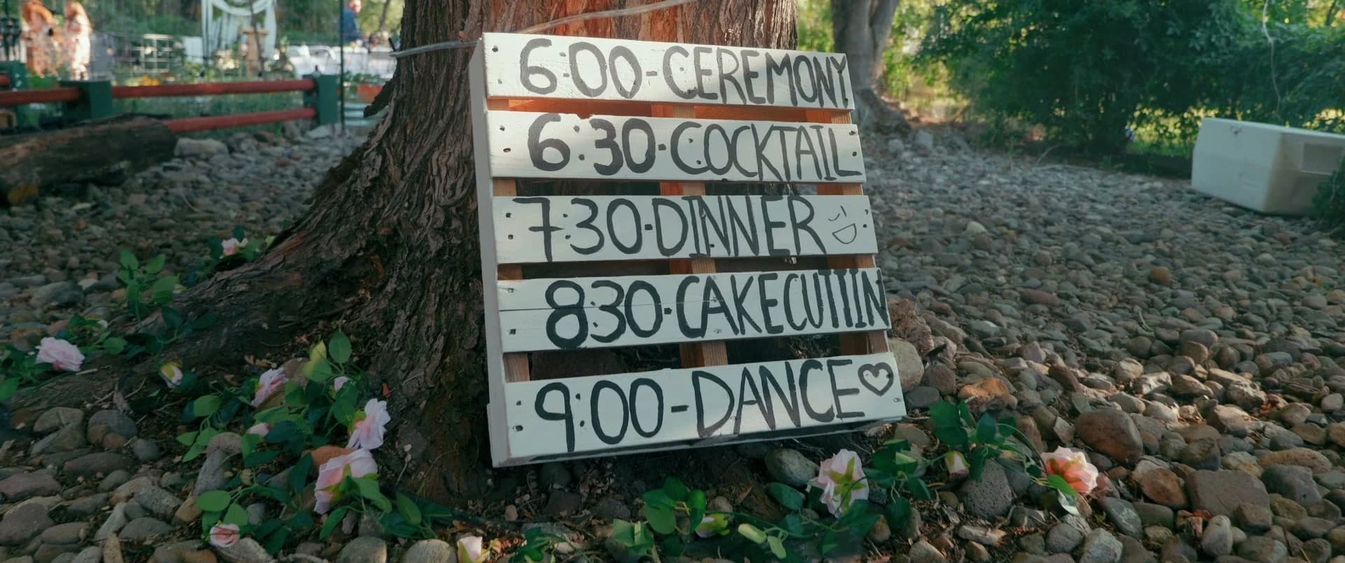 A hand-painted sign with the day's schedule, ceremony at 6:00 and dancing at 9:00