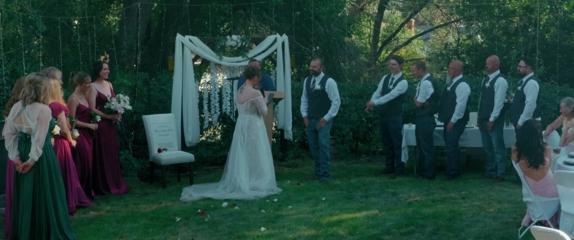 Juliet and James at the draped arch during the ceremony, the wedding party on either side