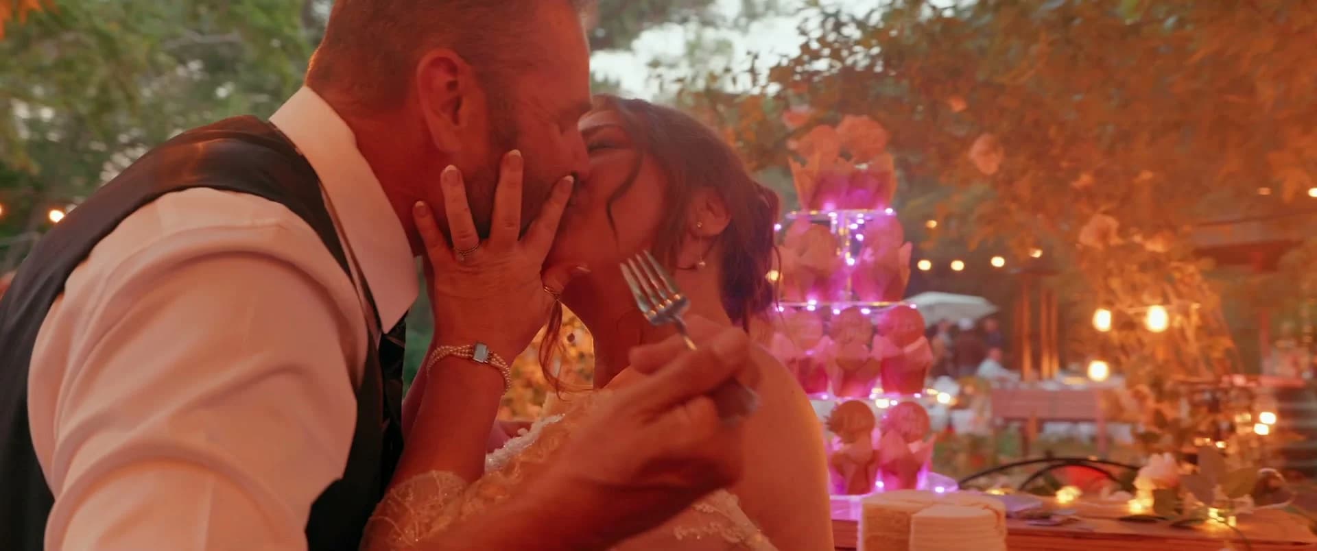 James + Juliet kissing by the cake in pink light