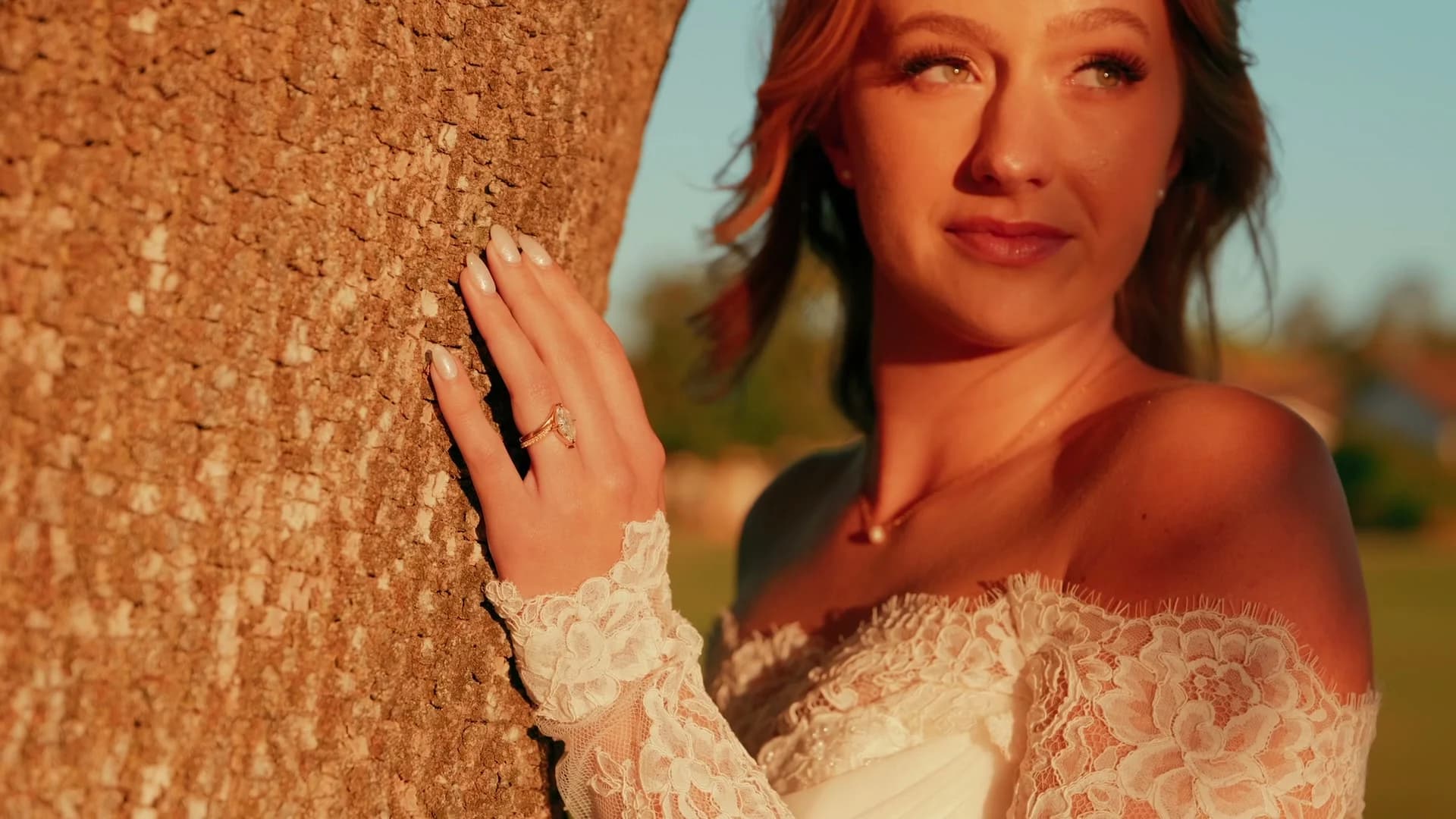 Kat in golden light against a tree trunk, her ring in view
