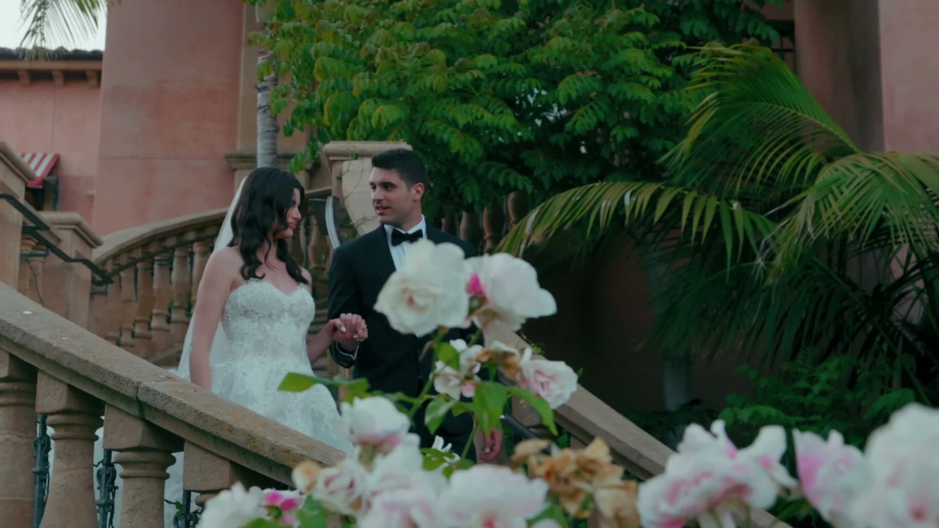 Theo + Kristen on a stone staircase lined with pink flowers