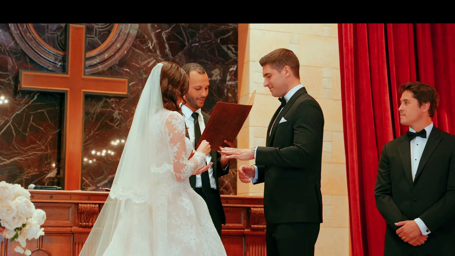 Theo + Kristen exchanging rings beside the tall wooden cross
