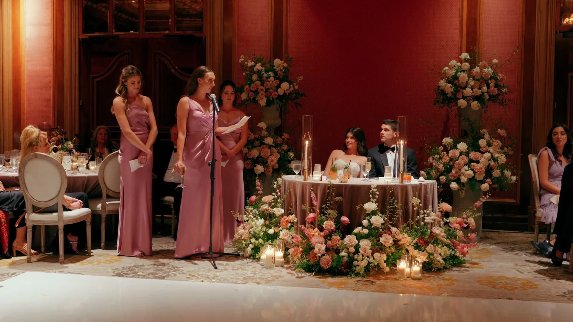 A bridesmaid's toast beside the sweetheart table and its pink flowers