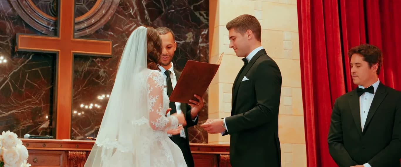 The officiant holding the vows book as Theo + Kristen exchange rings