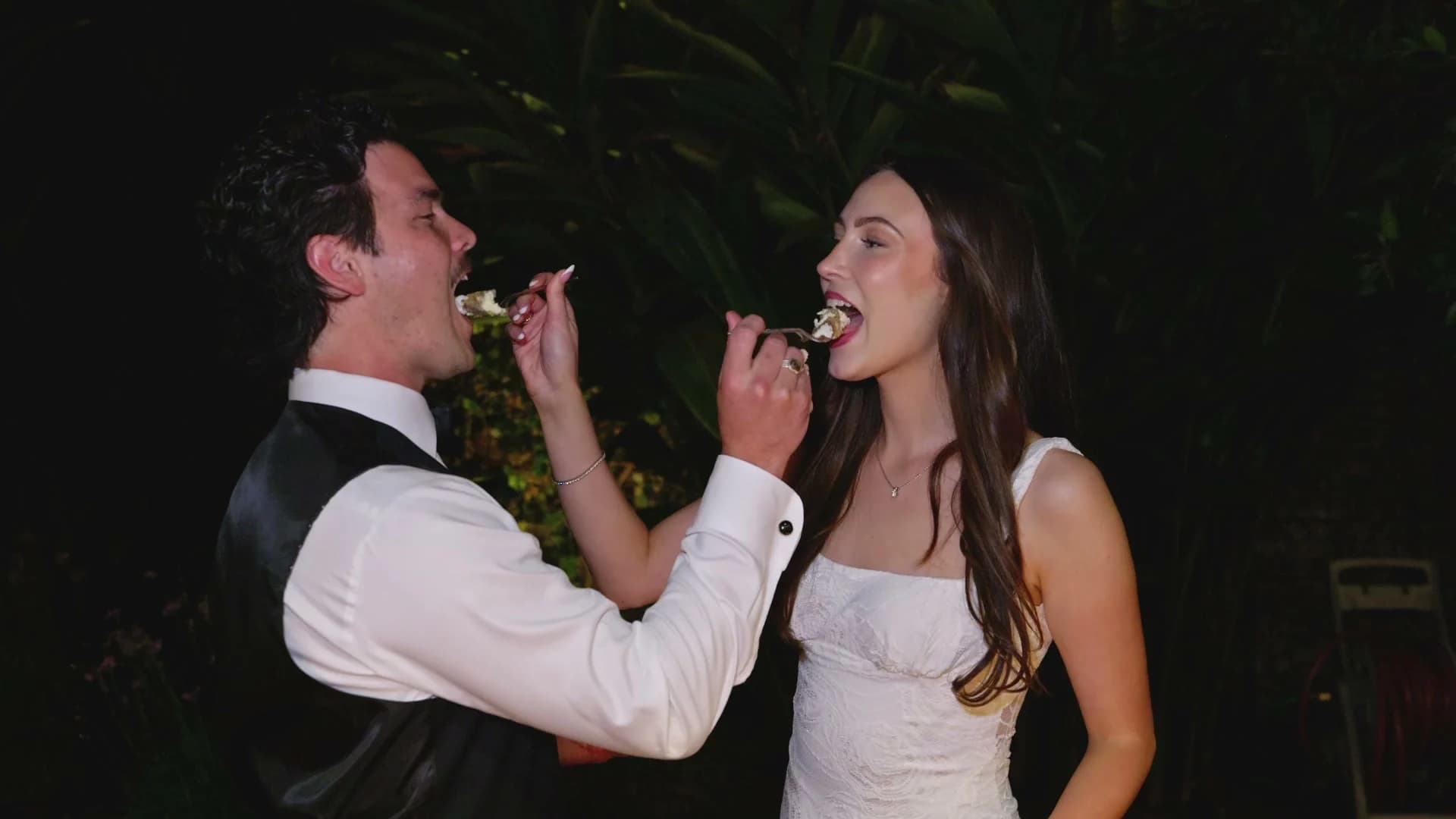 Zach + Madelin feeding each other cake at night