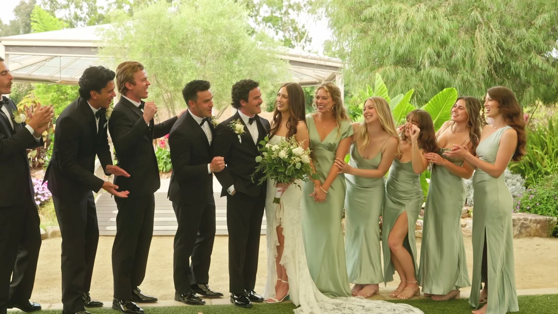 The wedding party laughing together in the garden