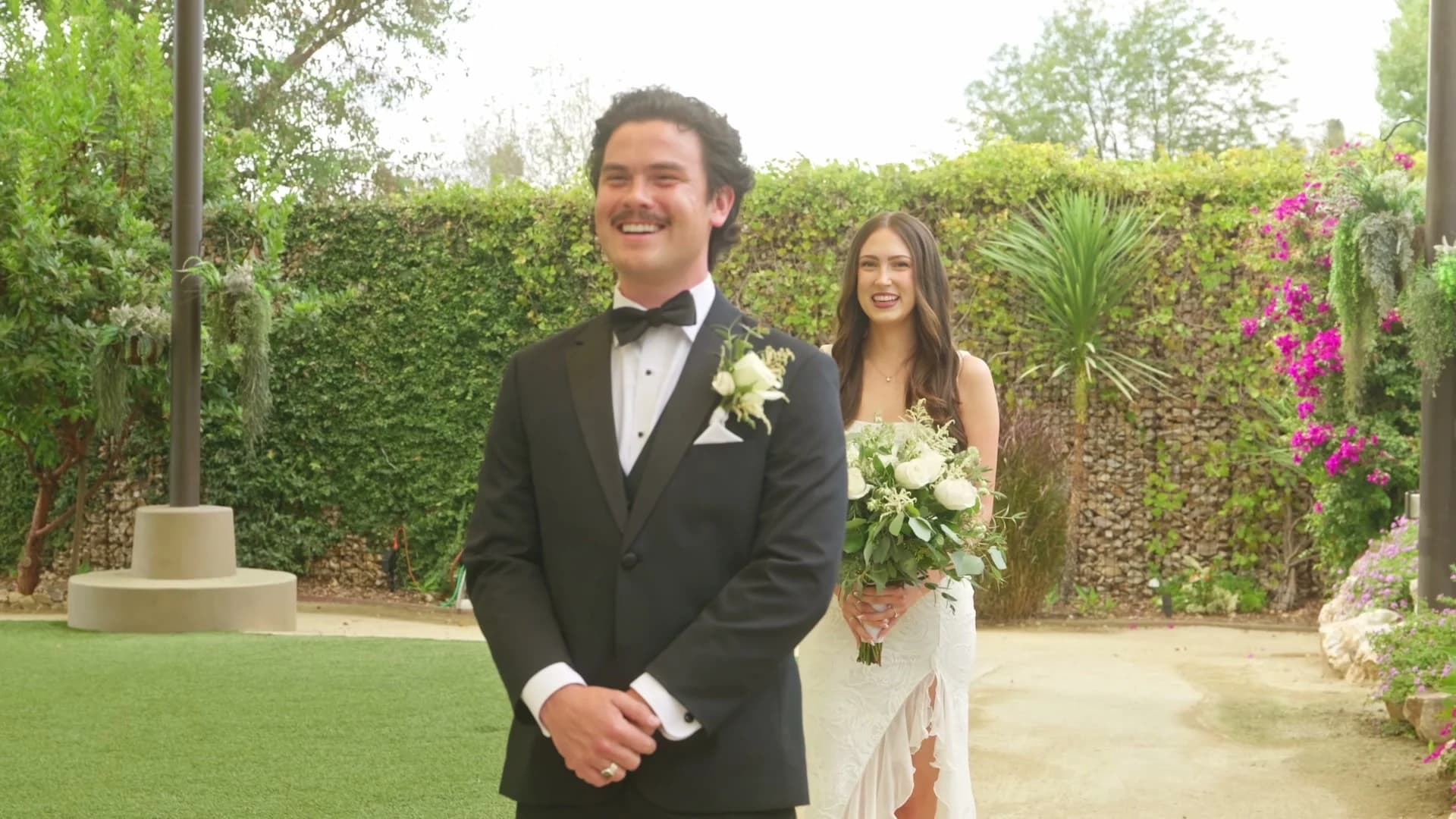 Zach smiling as Madelin walks up behind him for the first look