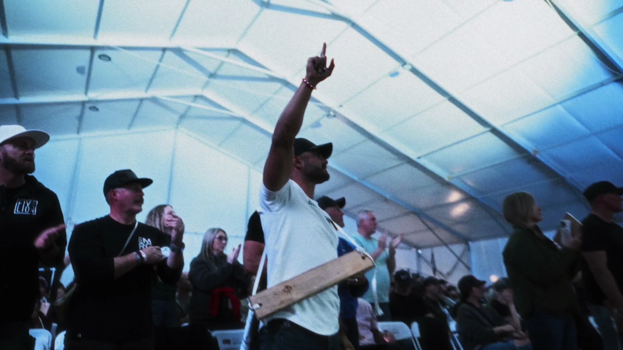 Men worshipping with raised hands inside the main tent at Emerge Men's Conference