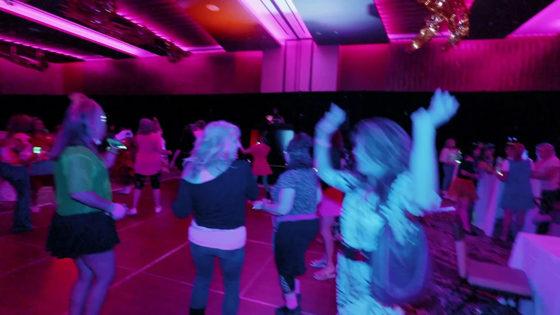 Attendees dancing under pink and blue lights at Adored Wife Weekend's evening party