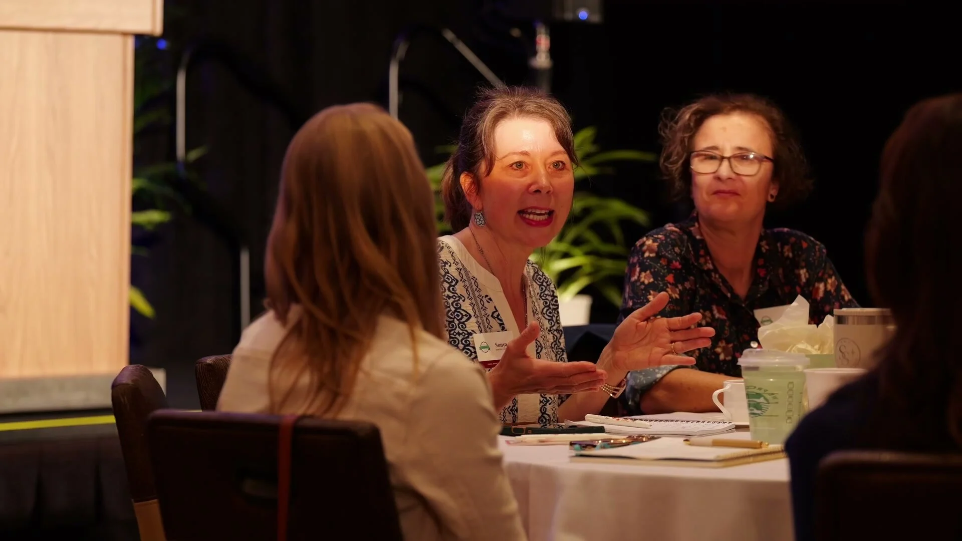 Attendees talking and laughing at a round table between conference sessions at Adored Wife Weekend, San Diego