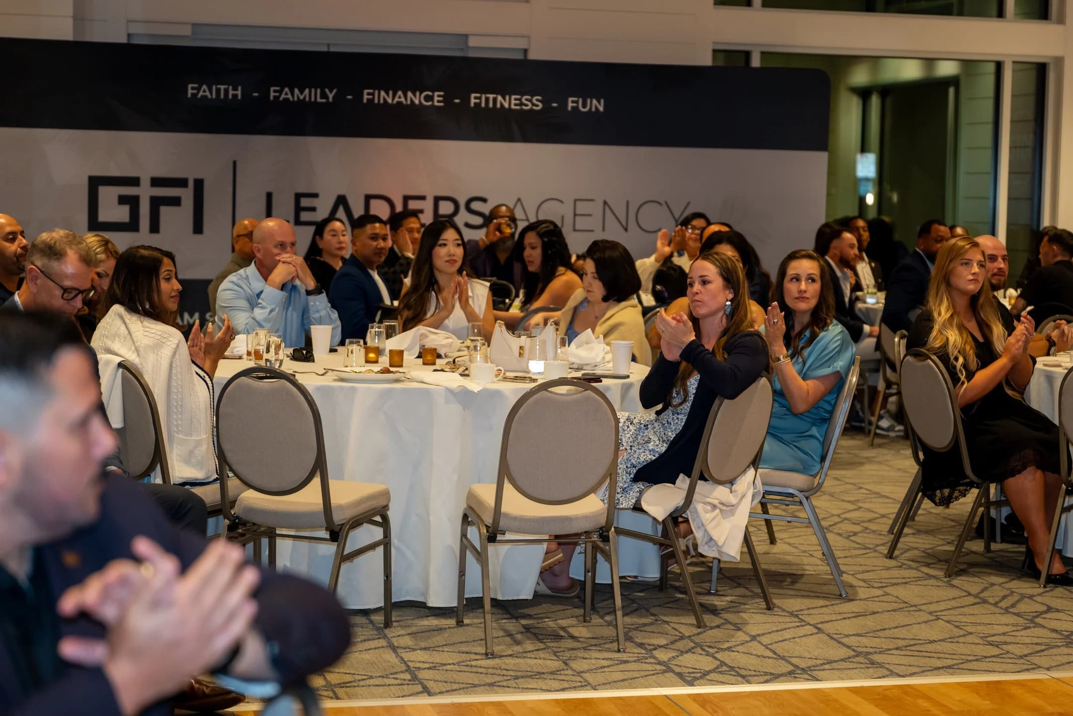 Guests at round tables in front of the GFI Leaders banner during the GFI conference dinner